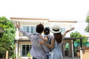 Familia feliz con su hijo que acaba de comprar casa viéndola desde afuera