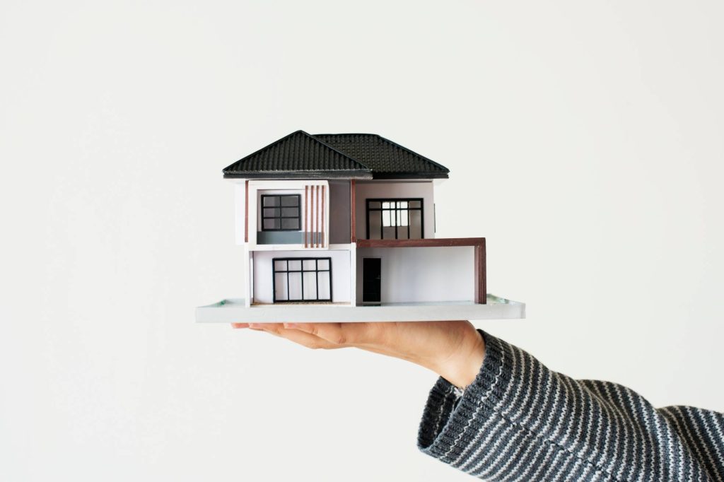 venta de casas, Mano que presenta casa modelo para campaña de préstamos hipotecarios