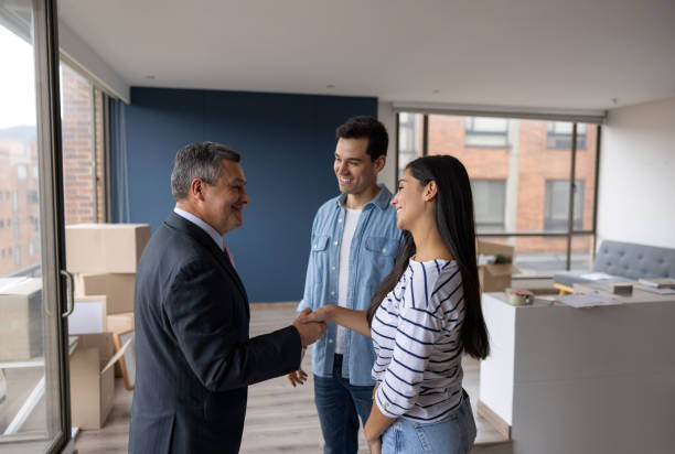 1.casas en venta. Una persona dándole la mano a una pareja que acaban de comprar su casa 
