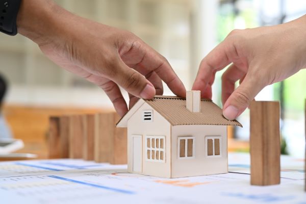 Imagen de dos personas que están tocando el prototipo de una casa haciendo alusión a la ventaja que tienen las casas en venta en Metepec.