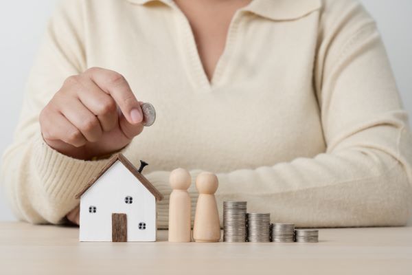 Casas en Querétaro; imagen de una persona haciendo una fila con dinero y algunos muñecos de madera que finalizan con una pequeña casa como inversión de una propiedad.
    