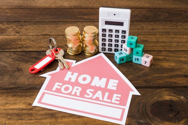 Casas en venta en Querétaro; una calculadora, unas llaves, monedas, dados y un letrero de for sale