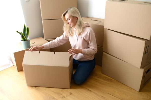 Departamentos en renta en Querétaro; imagen de una mujer feliz sacando sus pertenencias de las cajas pues se ha mudado a un departamento agradable.