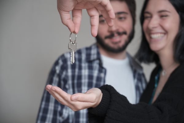 Departamentos en venta en Querétaro; imagen de una pareja recibiendo las llaves de un departamento que compraron.