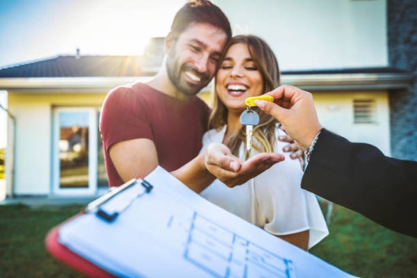Casas en venta en Monterrey; una pareja feliz, mientras el hombre recibe las llaves