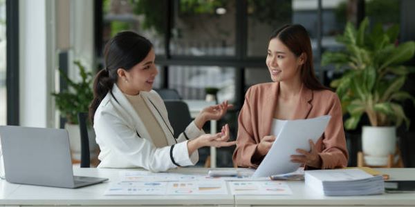 Departamentos en venta en Metepec; dos mujeres en una oficina hablando y con contratos en la mano. 