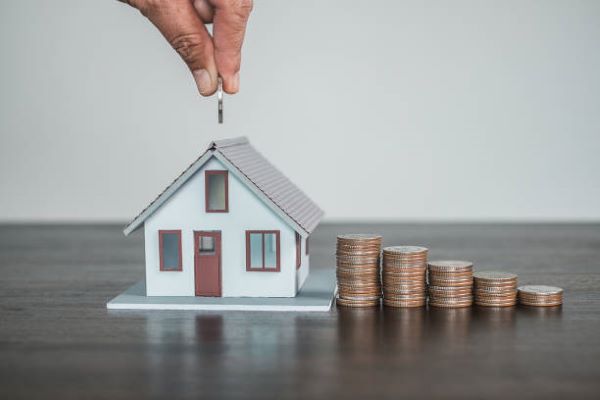 Casas en renta en Metepec; Una persona metiendo una moneda a una alcancía en forma de casa