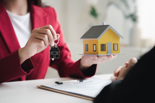 Departamentos en venta en Metepec; persona de saco rojo con casa amarilla