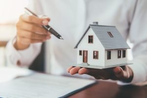 Concepto de venta de bienes raíces, mansión miniatura con llaves a un lado