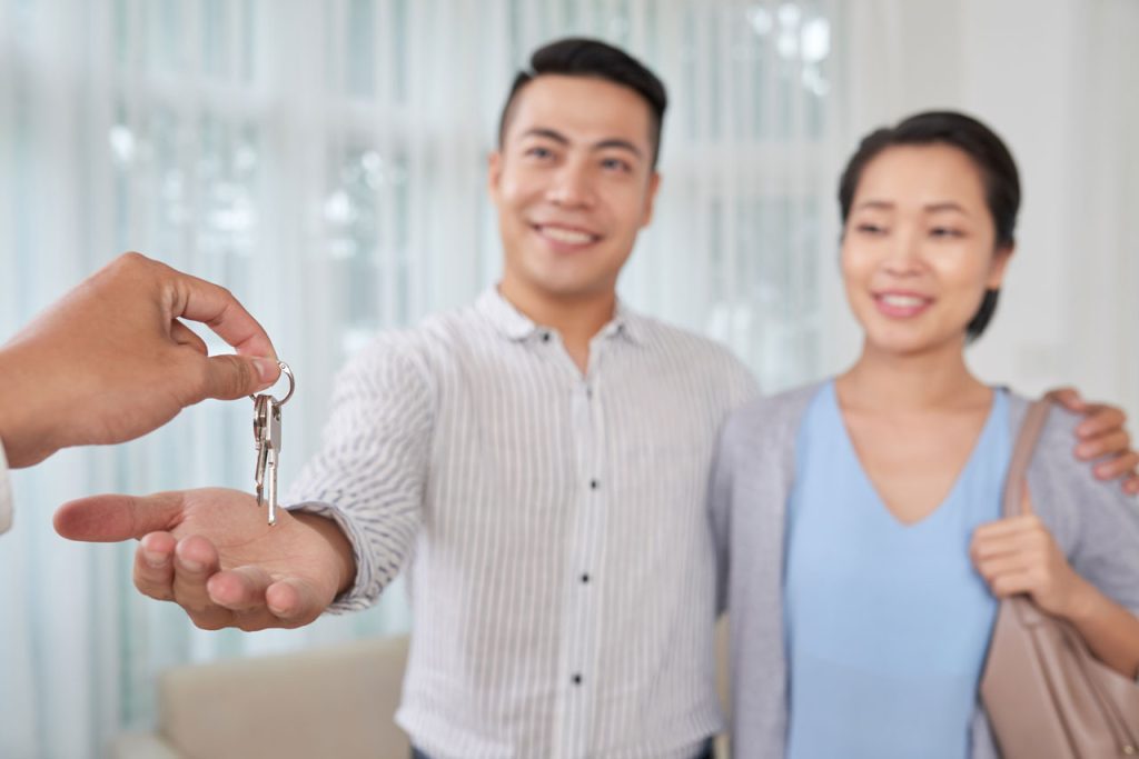 Broker dando las llaves de departamentos en venta a pareja