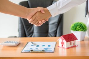 Manos del agente de una inmobiliaria y del cliente estrechándose la mano después de firmar un contrato