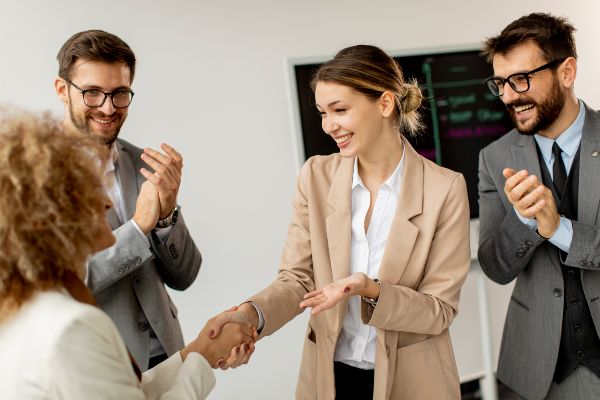 Emprender un negocio en México; dos mujeres estrechando su mano después de una junta con su equipo.