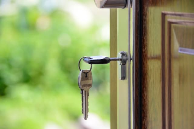 Inmobiliaria; imagen de una pequeña casa formada por figuras de plástico y señalada con una lupa.