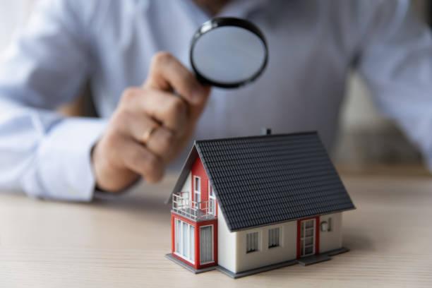 Agencia inmobiliaria;Una persona con una lupa observando una casa