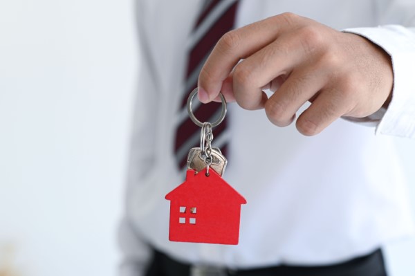 Qué es una inmobiliaria; imagen de un hombre sosteniendo unas llaves cuyo llavero es de una casa de color rojo.