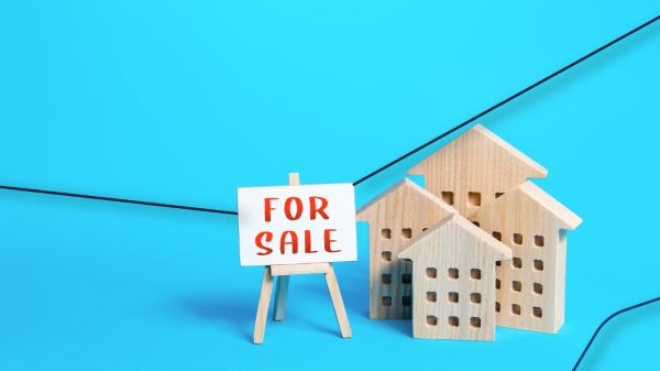 Casa en venta; imagen de pequeñas casas de madera con un pequeño cartel que pone en venta este tipo de propiedades.