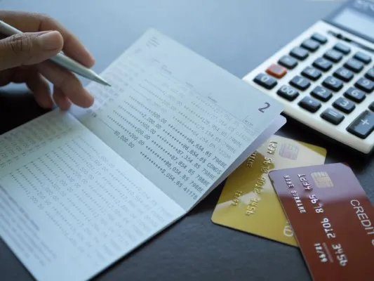 Una persona que acaba de entender cómo mejorar su historial crediticio que se encuentra haciendo números en una hoja.
