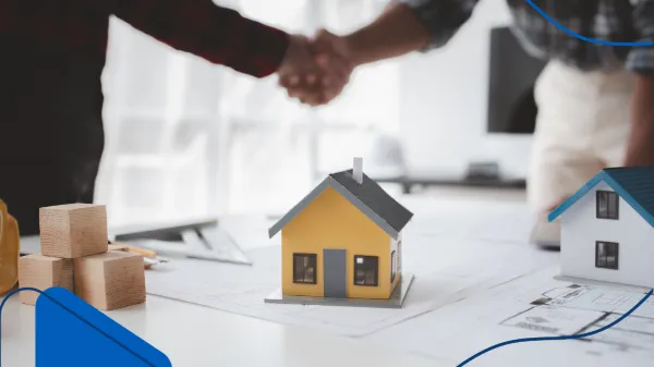 Foto de una casa pequeña de madera amarilla y dos personas cerrando el trato de la compra de casa al fondo