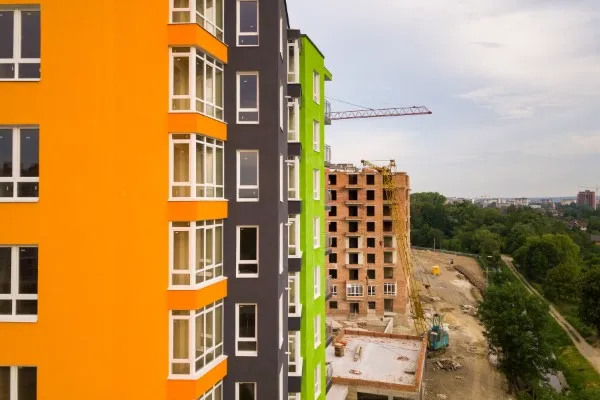 Fotografía de departamentos nuevos en edificios de colores naranja, gris y verde lima.
